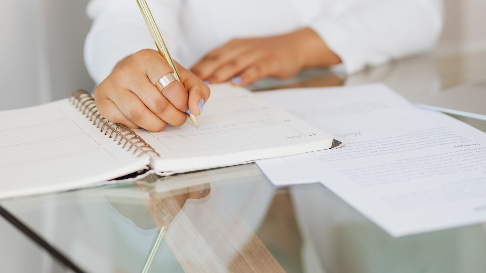 A woman writing in her planner with a gold pen — the quiet, intentional space where a renewed money mindset begins